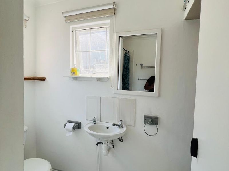 A compact bathroom featuring a wall-mounted basin, toilet, and classic black and white checkered floor tiles.