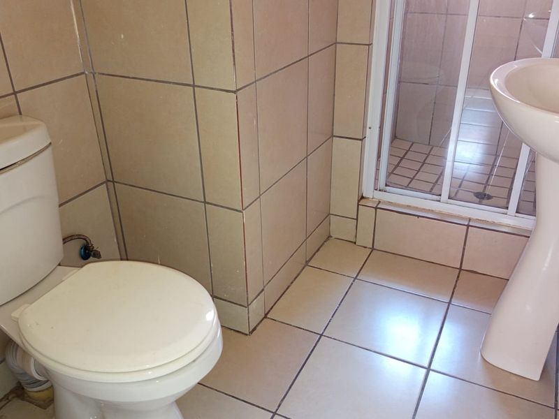 A functional bathroom featuring a pedestal basin, toilet, and a separate shower enclosure with tiled finishes throughout.