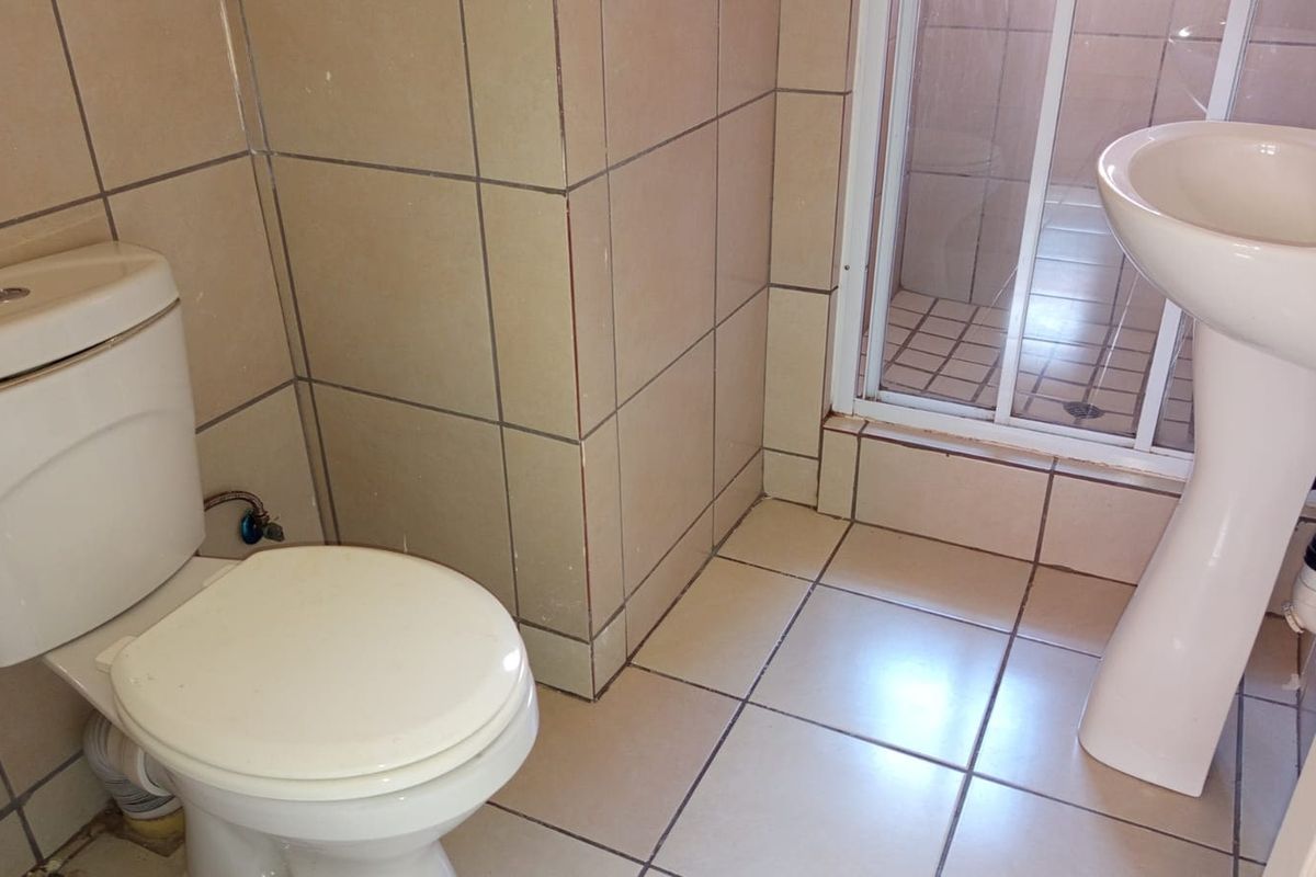 A functional bathroom featuring a pedestal basin, toilet, and a separate shower enclosure with tiled finishes throughout.