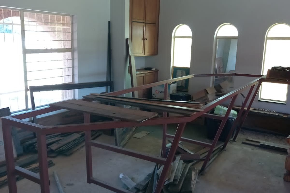 Spacious room featuring a timber ceiling, arched windows, and built-in cabinetry, currently in a state of renovation and requiring finishing touches.