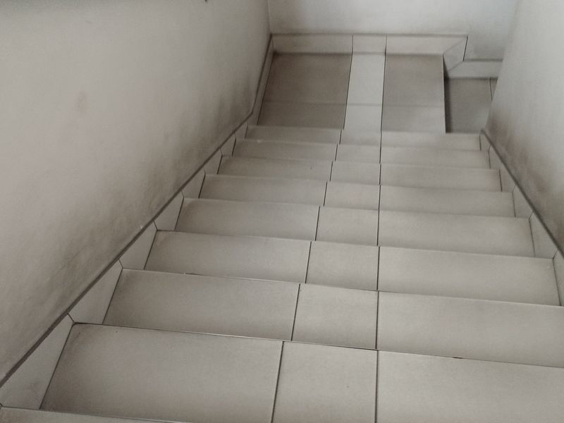 A tiled staircase interior showing signs of wear and scuffing on the surrounding walls.