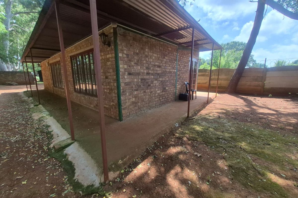 Rear view of a face brick commercial building featuring a covered patio area and a surrounding precast concrete boundary wall.