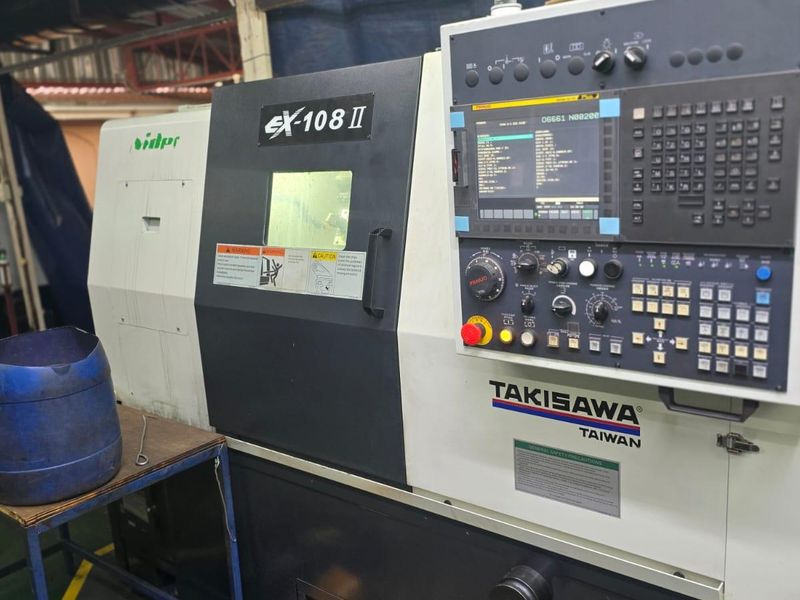 A Takisawa EX-108 II CNC lathe machine situated in an industrial utility space, featuring an integrated control panel and signal tower light.