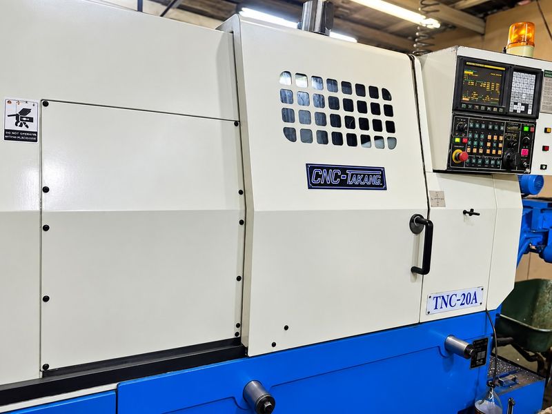 A well-maintained CNC-Takang TNC-20A industrial lathe machine featuring an integrated control panel and protective safety enclosure for precision manufacturing operations.