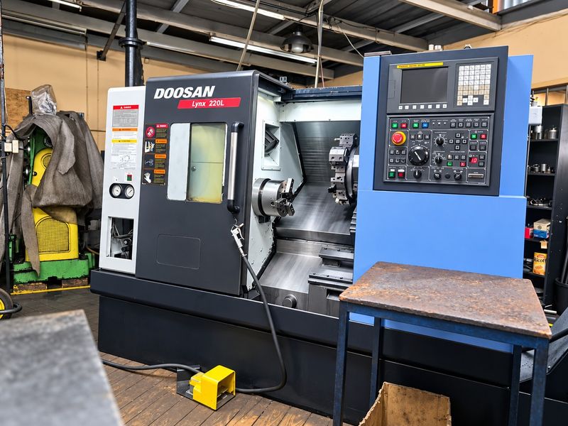 Industrial workshop space featuring a Doosan Lynx 220L CNC lathe machine with exposed ceiling structure and durable flooring.