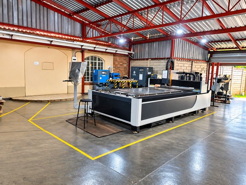 Spacious industrial utility area featuring exposed steel roof trusses, polished concrete flooring, and robust brick wall construction, suitable for manufacturing or workshop operations.