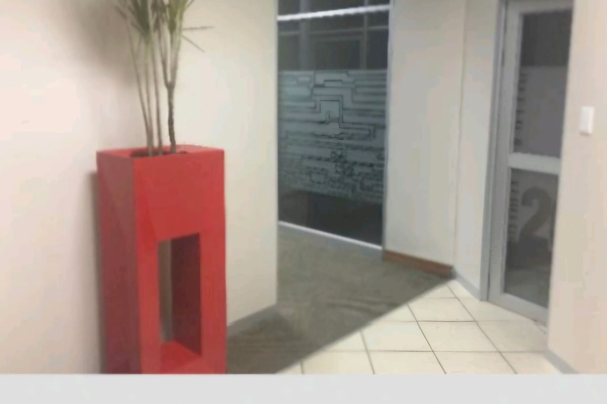 A commercial office hallway featuring tiled flooring, a glass-paneled door, and a frosted glass partition.