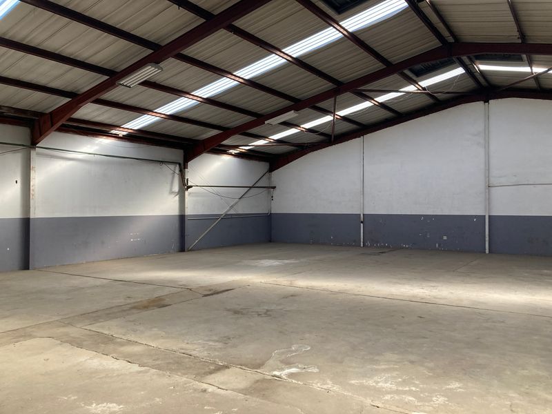 Spacious industrial warehouse unit featuring a high-clearance steel portal frame, concrete flooring, and natural light provided by integrated roof skylights.
