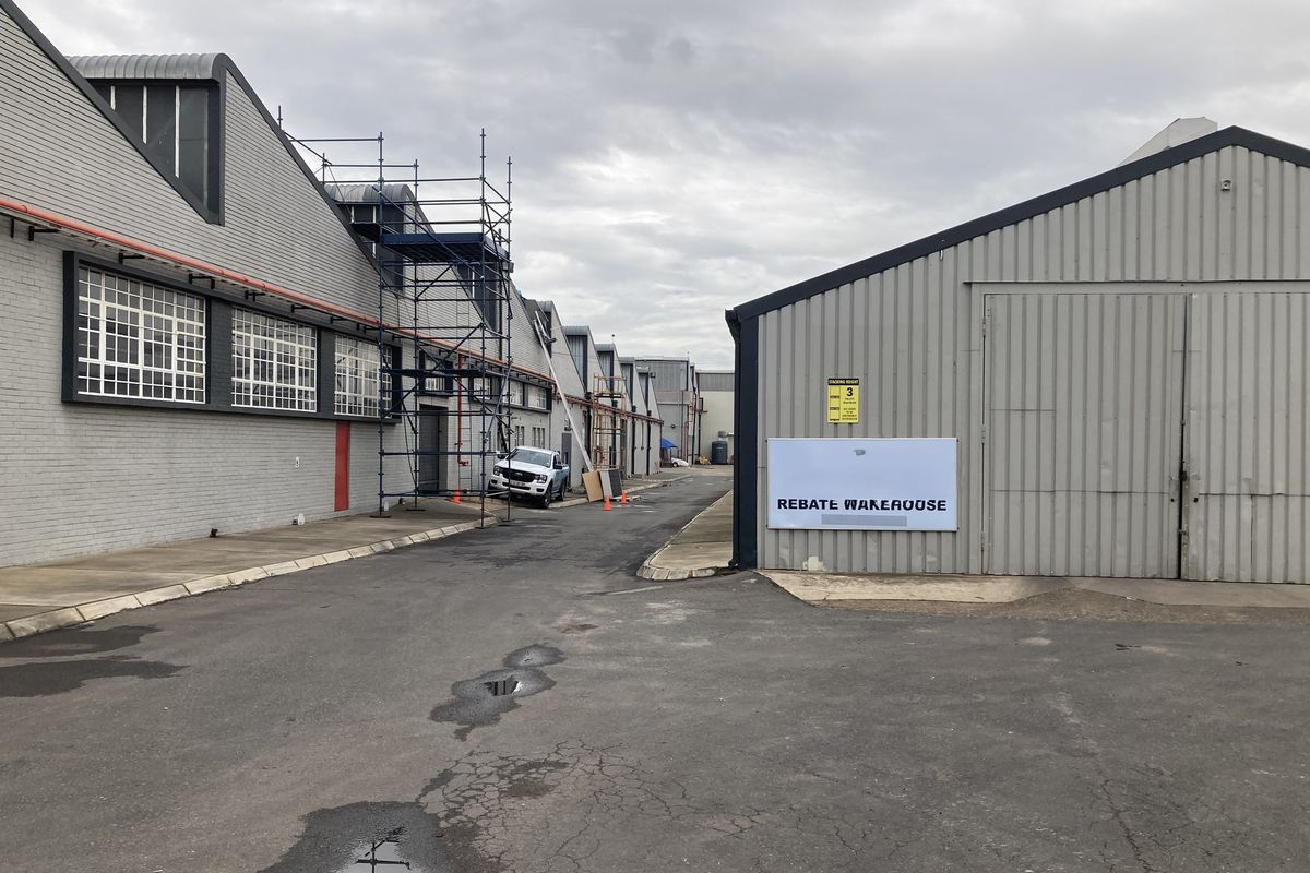 Exterior view of an industrial warehouse complex featuring metal cladding, steel-framed windows, and paved access driveway.