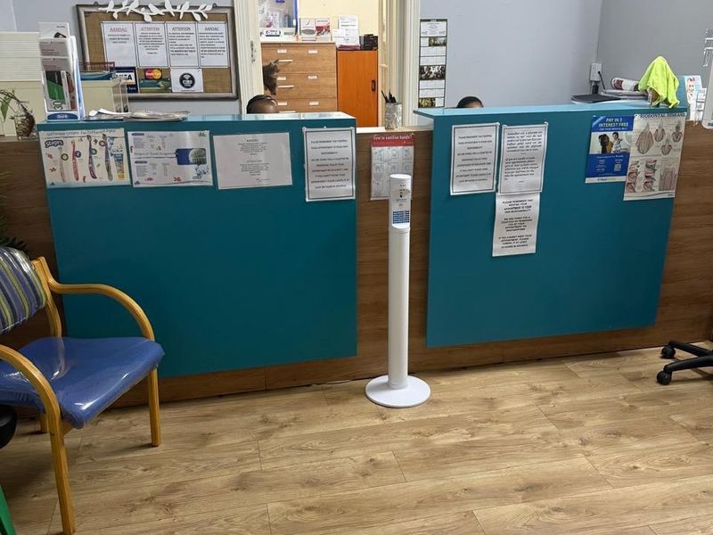 A commercial reception area featuring a built-in service counter, laminate wood-look flooring, and a wall-mounted air conditioning unit.