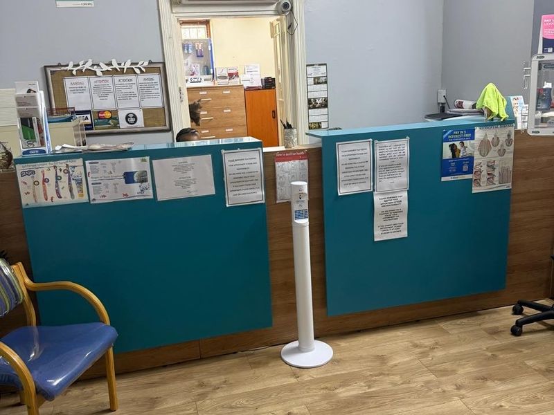 Commercial reception area featuring a built-in service counter, laminate wood flooring, and wall-mounted air conditioning unit.