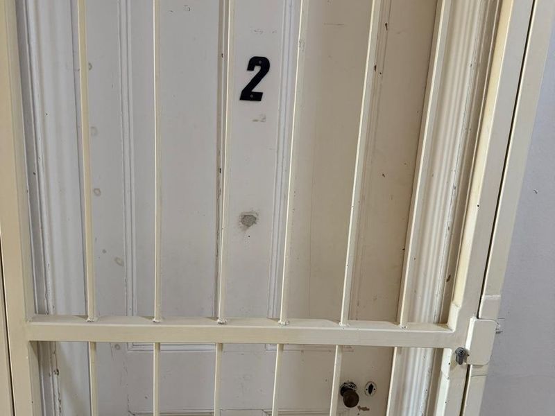 A secure entry point featuring a white panelled door protected by a fixed metal security gate.