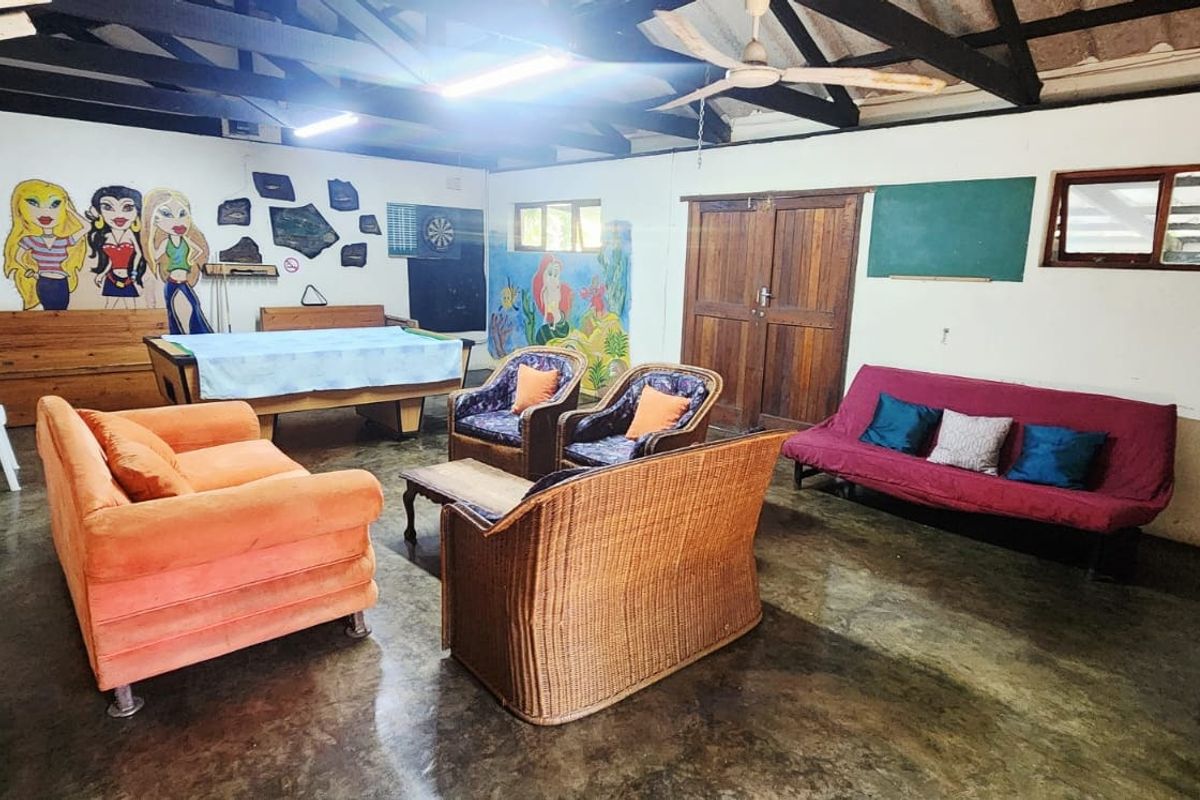 Spacious living area featuring exposed timber roof trusses, polished concrete flooring, and double timber doors, offering a versatile space for recreation or relaxation.