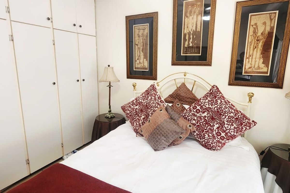 A bedroom featuring floor-to-ceiling built-in cupboards providing ample storage space.