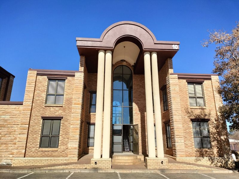 Front elevation of a commercial building featuring a prominent arched portico with classical columns and a double-height glass entrance facade.