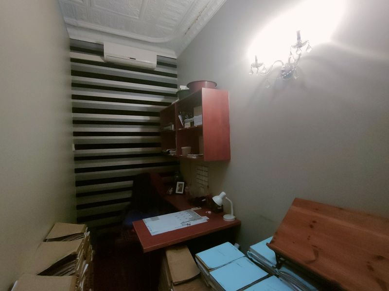 A compact office space featuring built-in cabinetry, wall-mounted air conditioning, and decorative ceiling detailing.