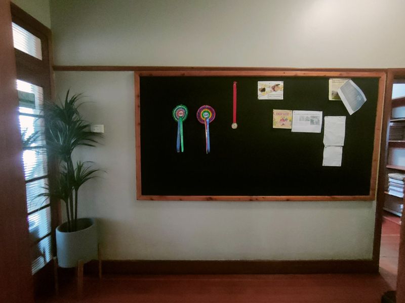 A commercial hallway featuring a large wall-mounted notice board with a wooden frame and timber door trim.
