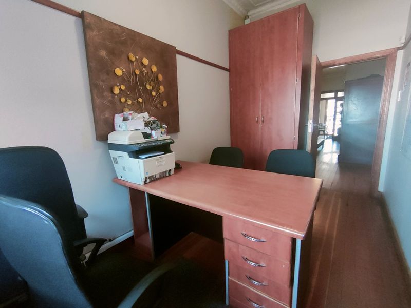 A functional office space featuring built-in cabinetry, wooden flooring, and decorative wall molding, providing a professional environment for administrative tasks.