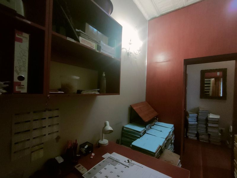 A functional office space featuring built-in wall cabinetry and a doorway leading to an adjacent room.
