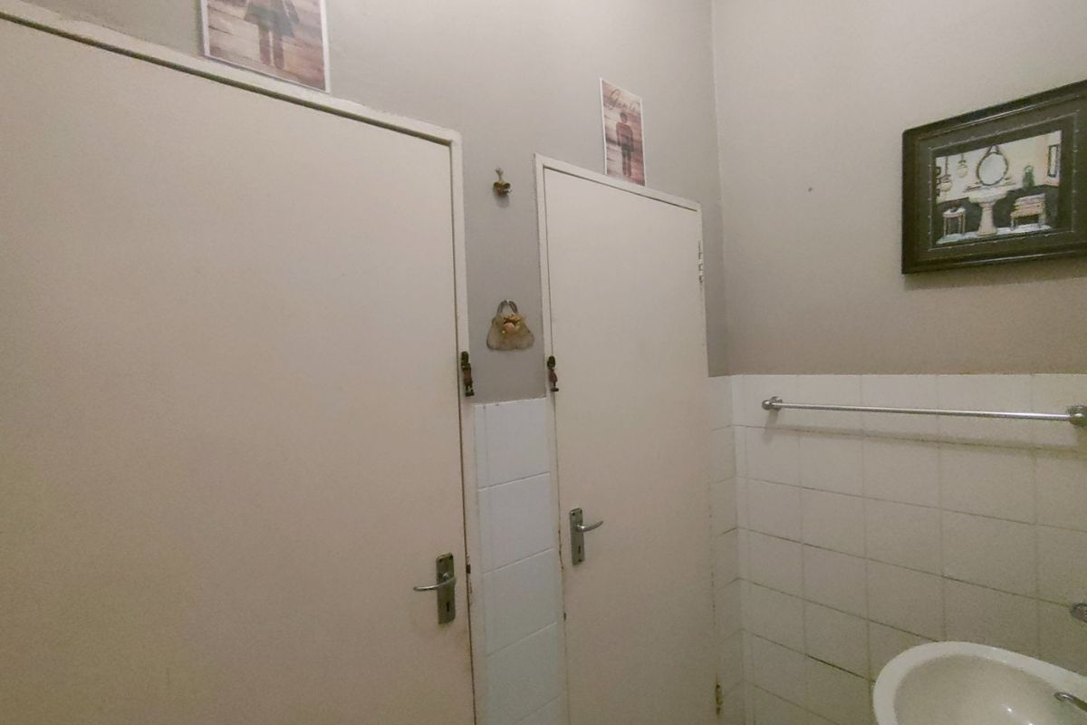 A functional bathroom space featuring tiled walls, a wall-mounted basin, and two internal doors providing access to adjacent areas.