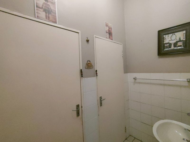 A functional bathroom space featuring tiled walls, a wall-mounted basin, and two internal doors providing access to adjacent areas.