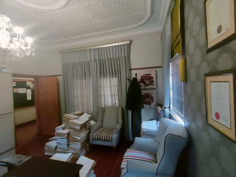 A professional office space featuring ornate pressed metal ceilings, decorative cornicing, and a classic chandelier, providing a traditional and formal atmosphere.