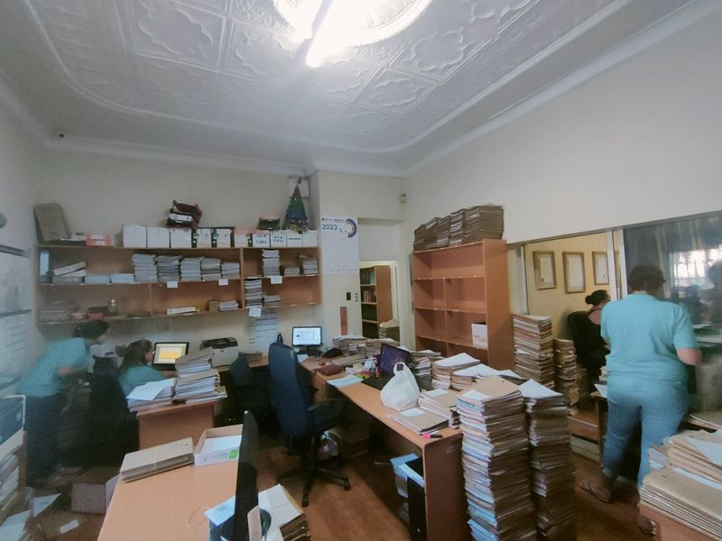 A functional commercial office space featuring traditional pressed metal ceilings and extensive built-in shelving units for document storage.