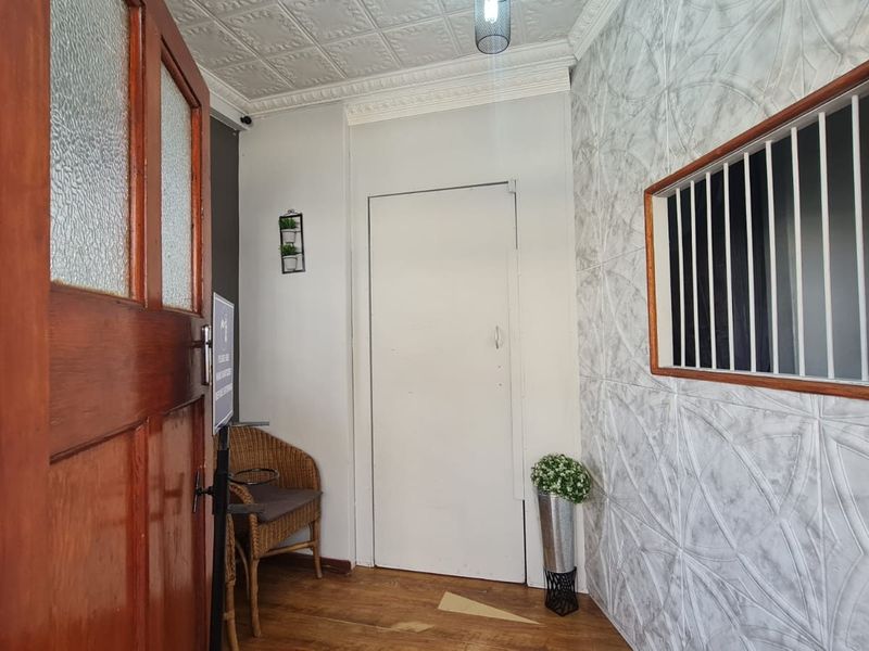 Entrance area featuring a timber door, textured wall paneling, and a decorative pressed metal ceiling with security-barred window.