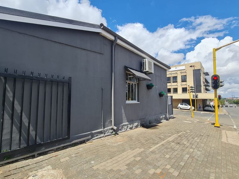 Exterior street-level view of a commercial property featuring a grey facade, security gate, and sidewalk access in a busy urban location.