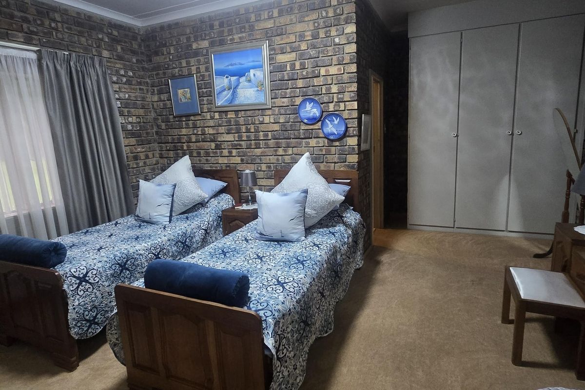 A bedroom featuring an exposed brick feature wall, built-in cupboards, and carpeted flooring.