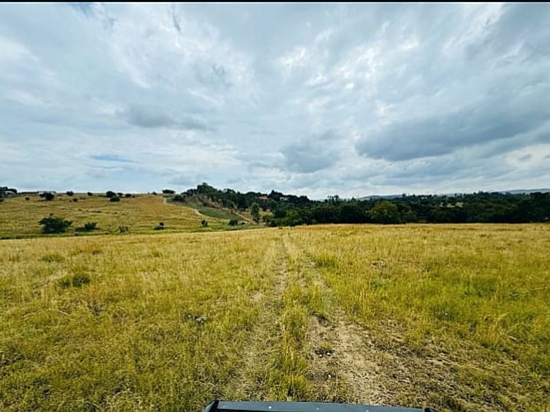 Expansive view of open grassland and rolling hills under a cloudy sky, showcasing the natural landscape of the property.
