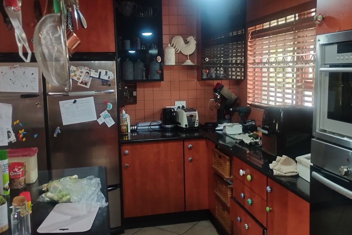 A functional kitchen featuring dark wood cabinetry, granite countertops, a built-in oven, and tiled backsplash with natural light from the window.