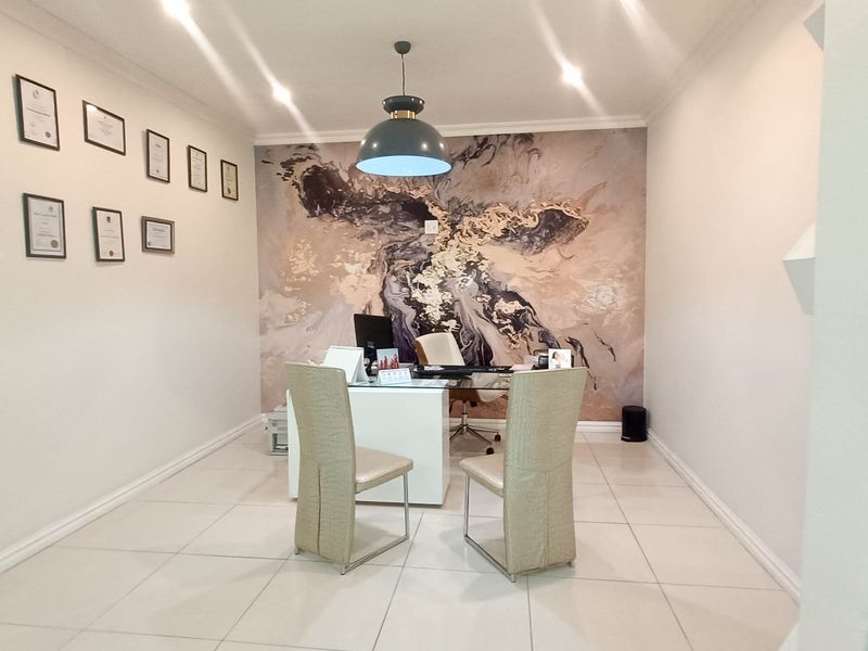 A professional office space featuring tiled flooring, recessed downlighting, coved cornicing, and a decorative feature wall.