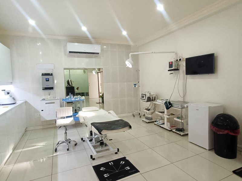 A well-maintained clinical utility space featuring tiled flooring, built-in cabinetry, and professional medical lighting, suitable for aesthetic or medical procedures.