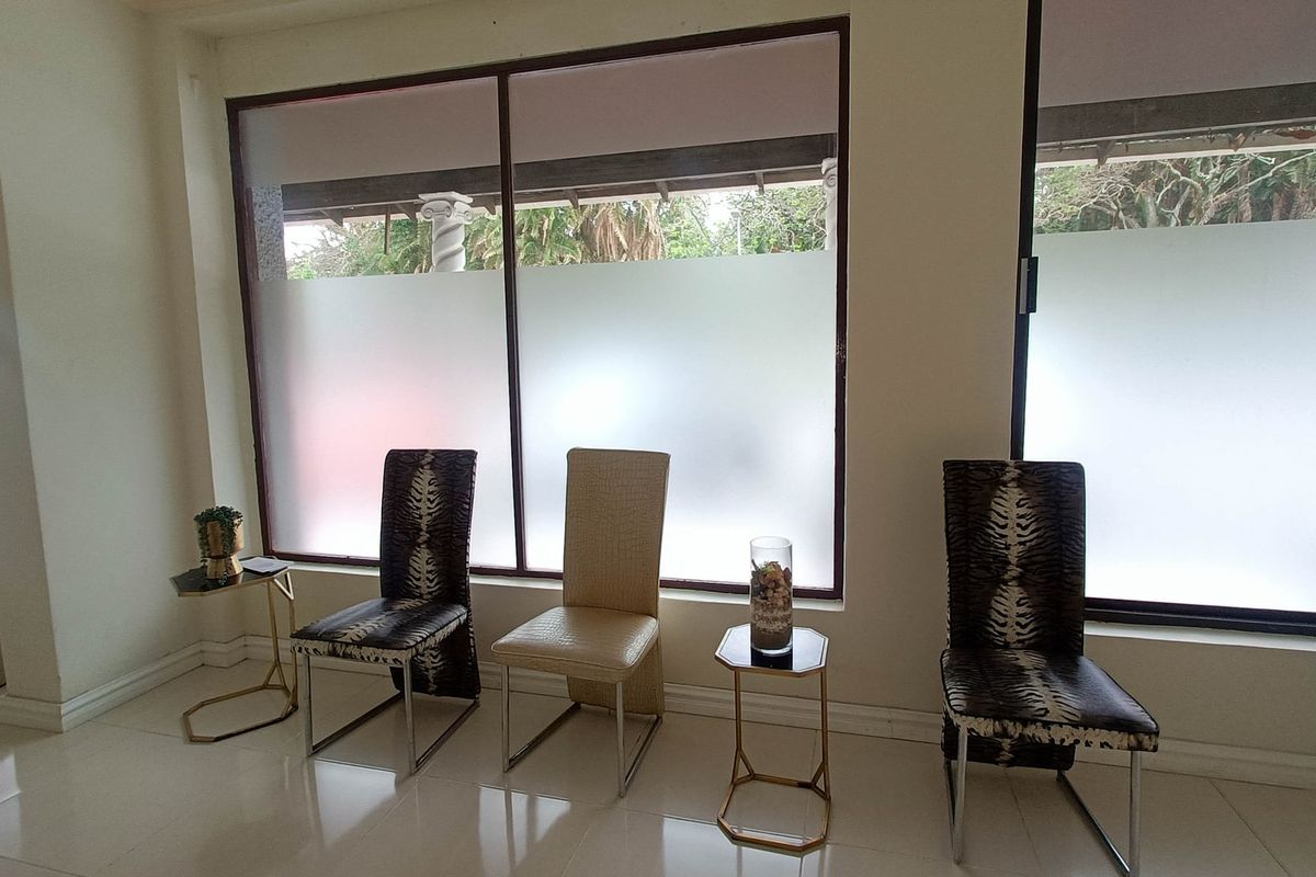 A bright waiting area or living space featuring large windows with frosted privacy film and clean tiled flooring.