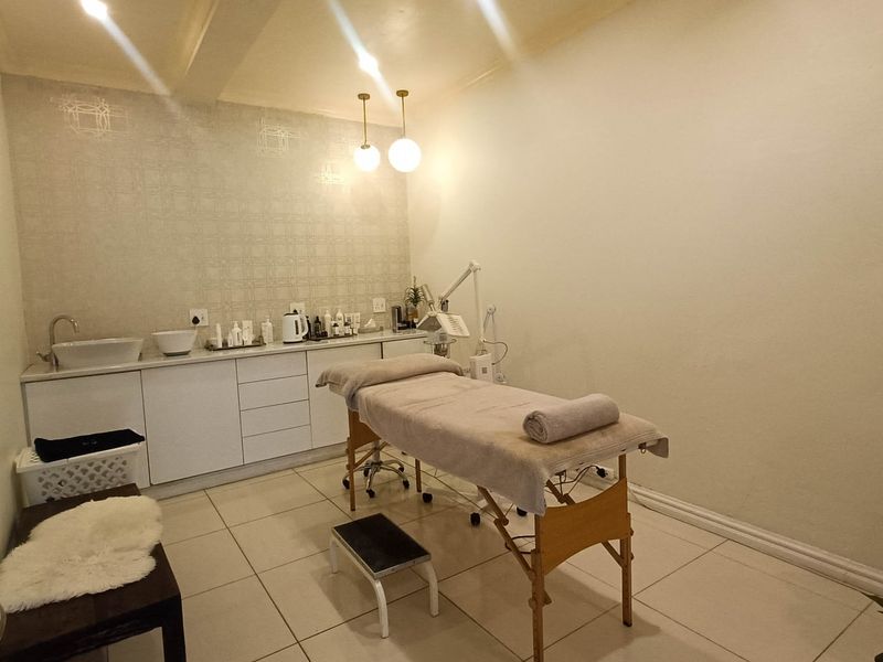 A clean and functional treatment room featuring built-in cabinetry with an integrated sink, tiled flooring, and modern pendant lighting.