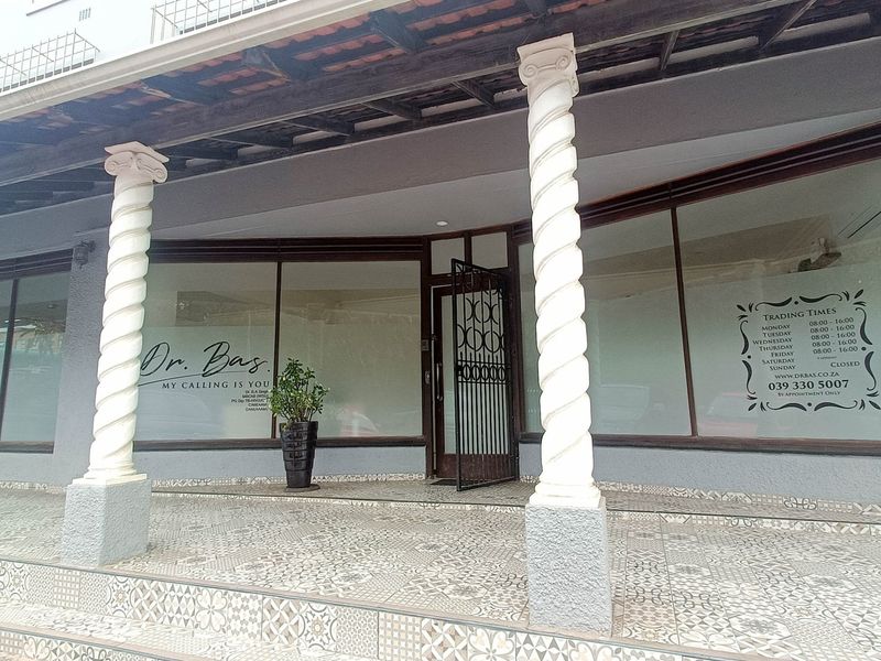 Commercial storefront entrance featuring decorative columns, a tiled porch area, and large glass display windows with professional signage.