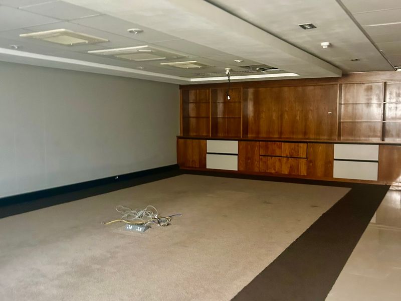 Spacious commercial office area featuring extensive built-in wooden cabinetry, recessed ceiling lighting, and neutral carpeting, suitable for a professional workspace.