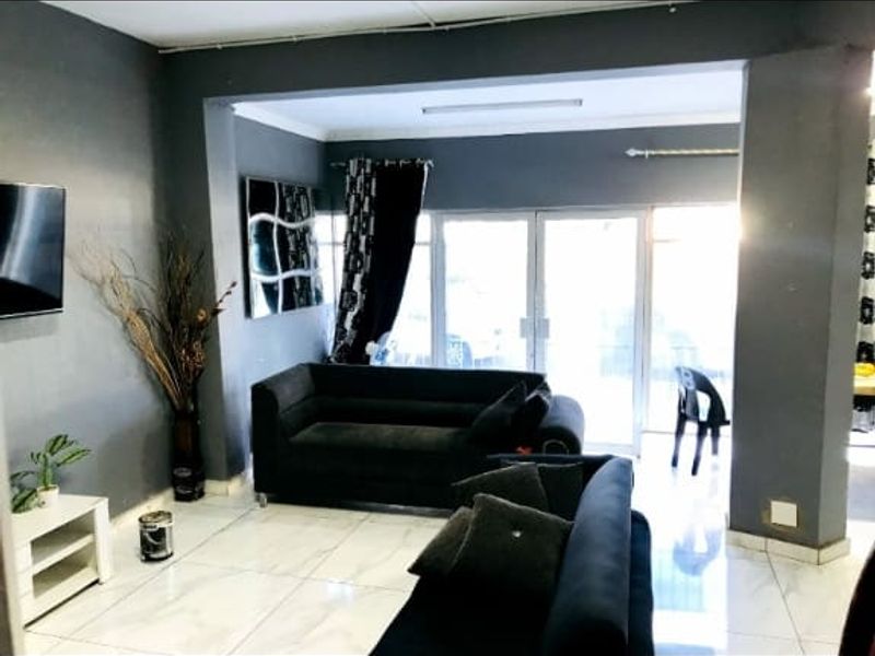 A living room area featuring tiled flooring and glass sliding doors leading to an outdoor space, with dark grey wall finishes.