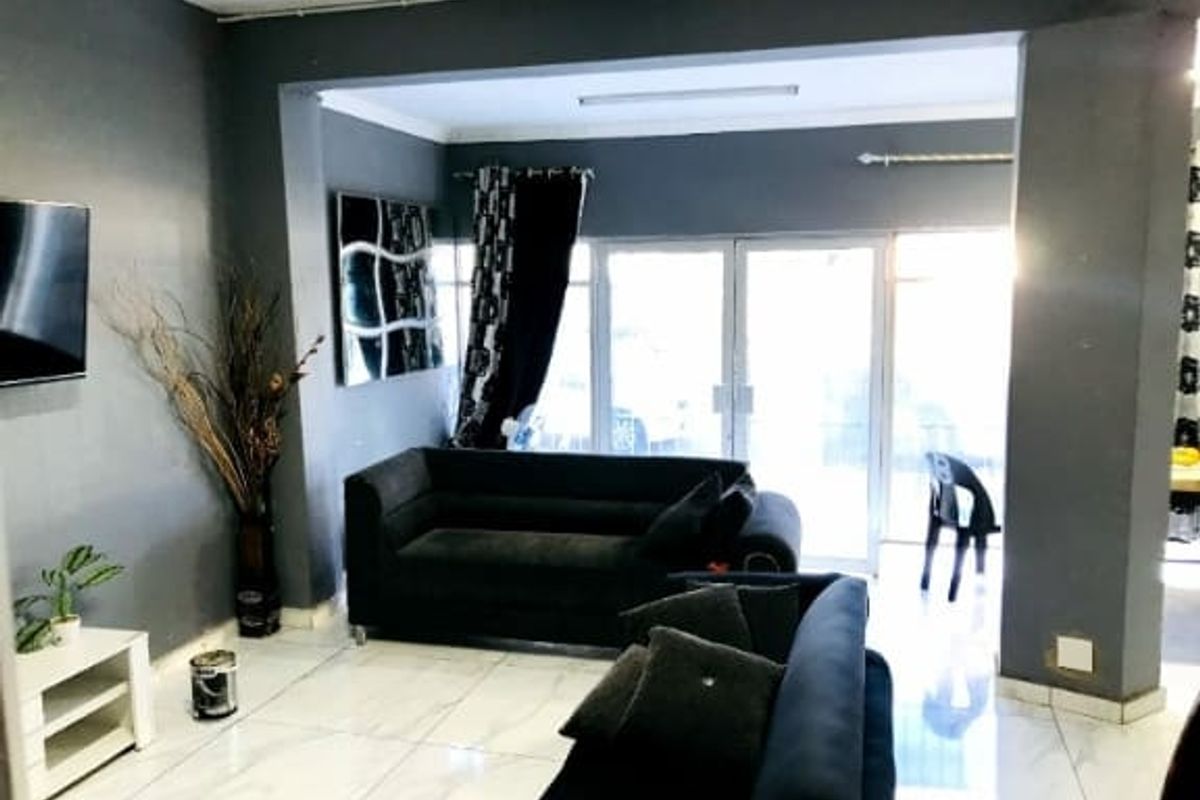 A living room area featuring tiled flooring and glass sliding doors leading to an outdoor space, with dark grey wall finishes.