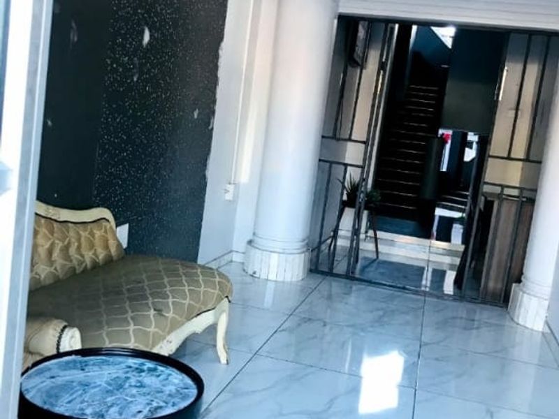 Entrance foyer featuring marble-look tiled flooring, decorative columns, and a feature wall leading to an internal staircase.