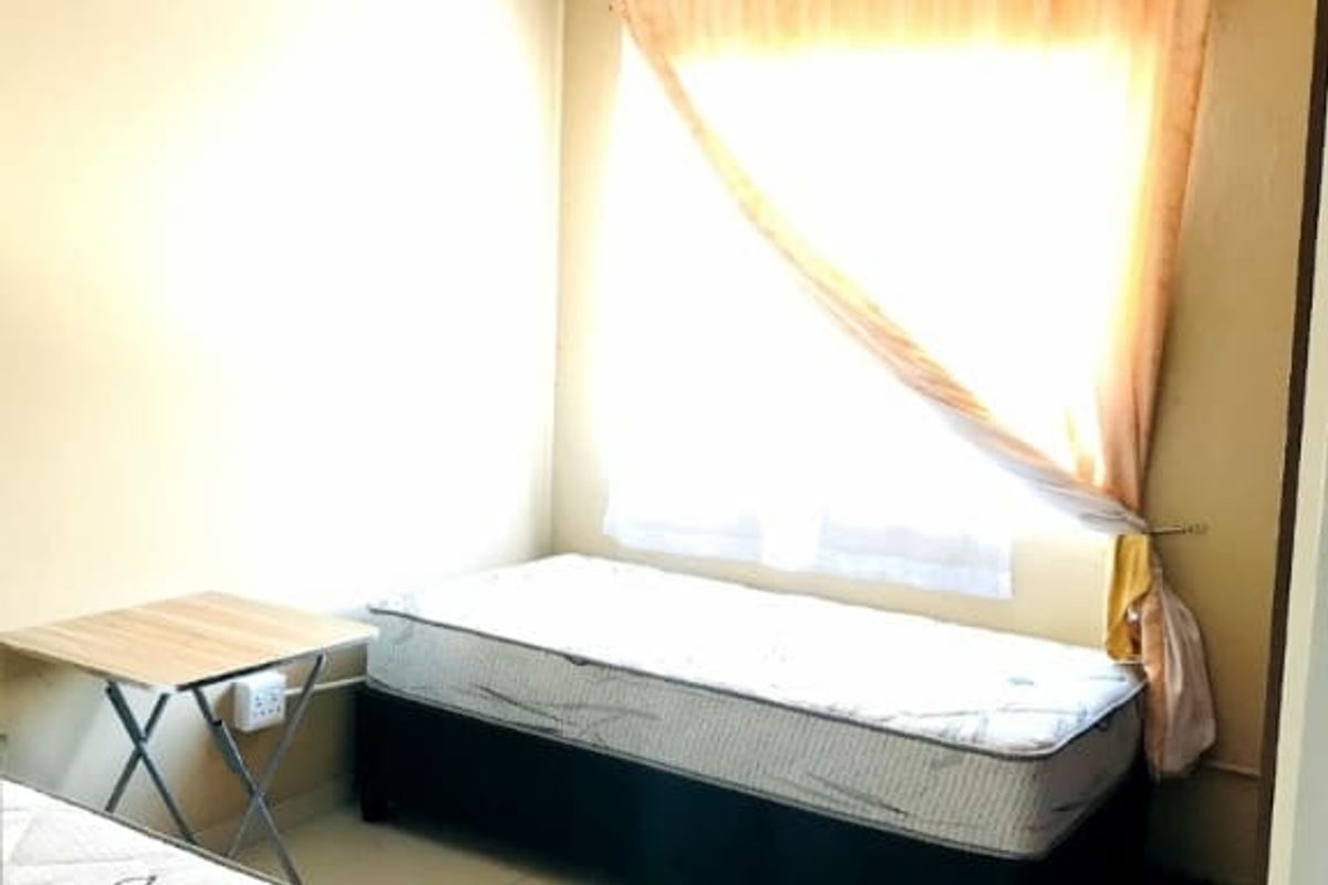 A simple bedroom featuring tiled flooring and neutral wall finishes, providing a functional space with natural light.