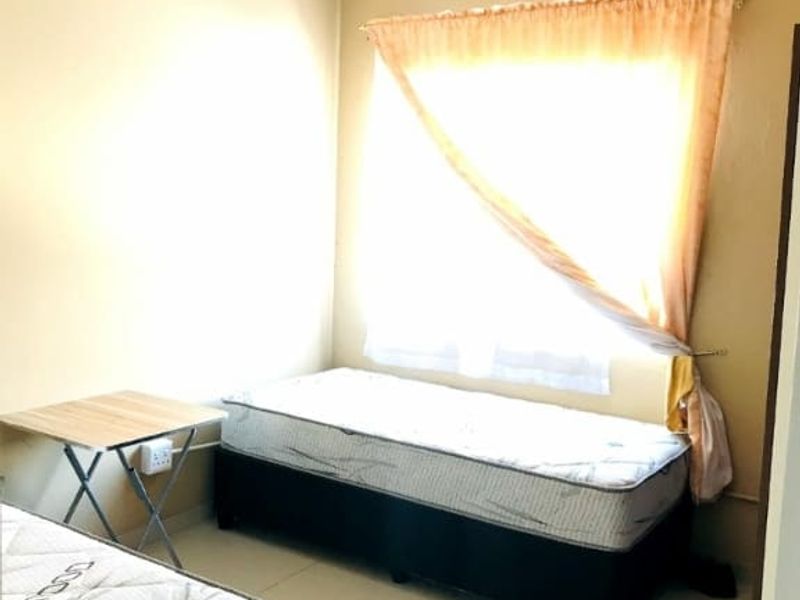 A simple bedroom featuring tiled flooring and neutral wall finishes, providing a functional space with natural light.