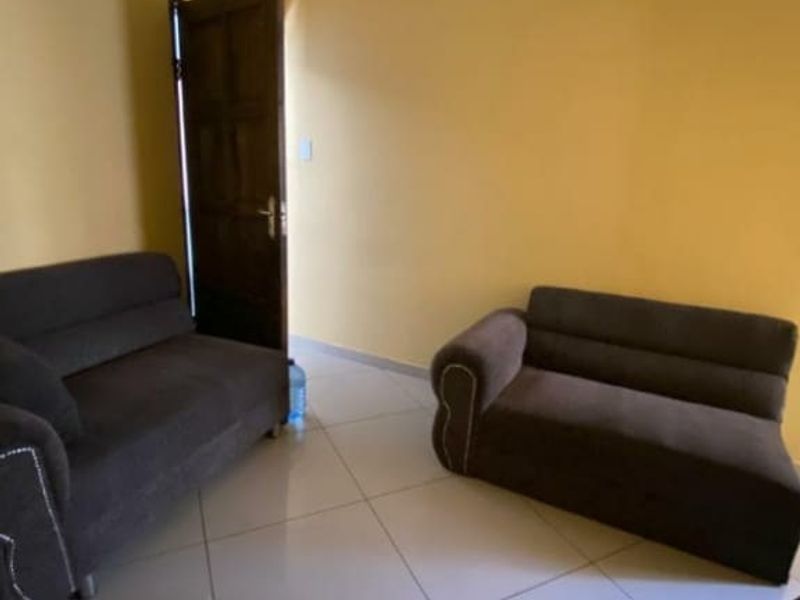 A simple living area featuring tiled flooring and yellow painted walls, providing a basic functional space for commercial or residential use.