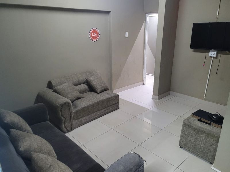 A functional living area featuring neutral tiled flooring and wall-mounted television infrastructure, suitable for commercial or office waiting room use.