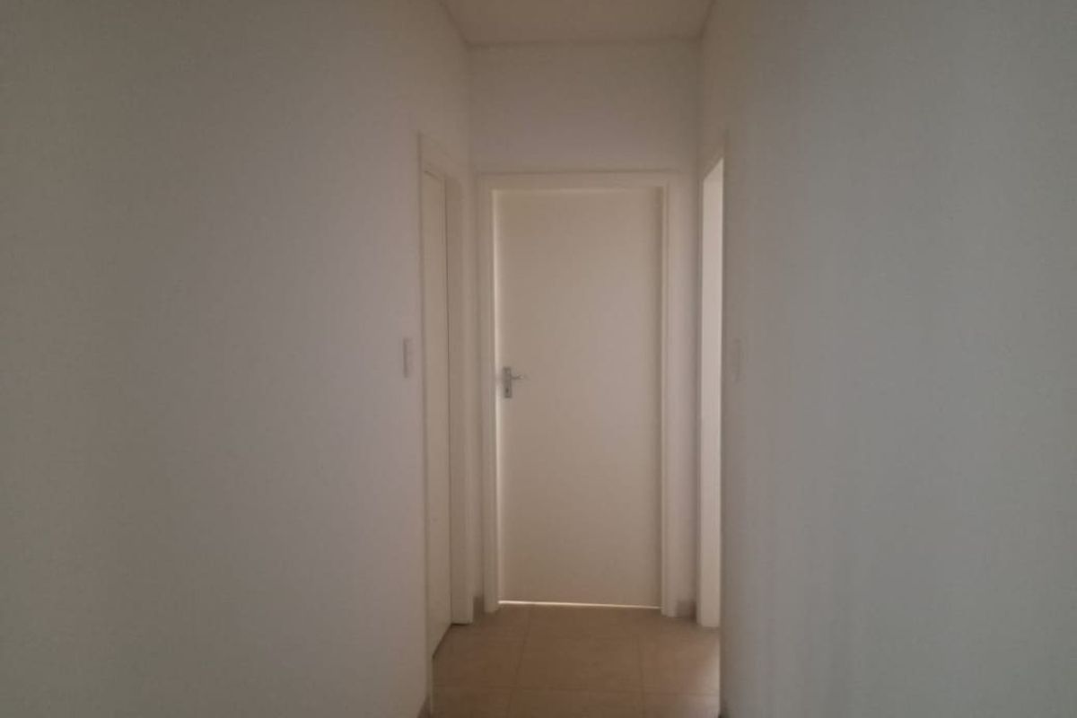A simple, neutral hallway featuring tiled flooring and multiple internal doors, providing access to various rooms within the commercial property.