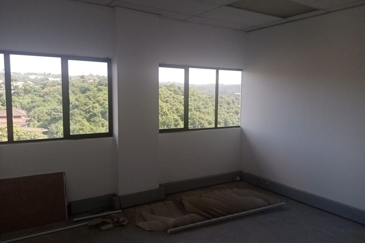 An empty commercial office space featuring large windows with scenic views, suspended ceilings, and unfinished flooring, ready for custom fit-out.