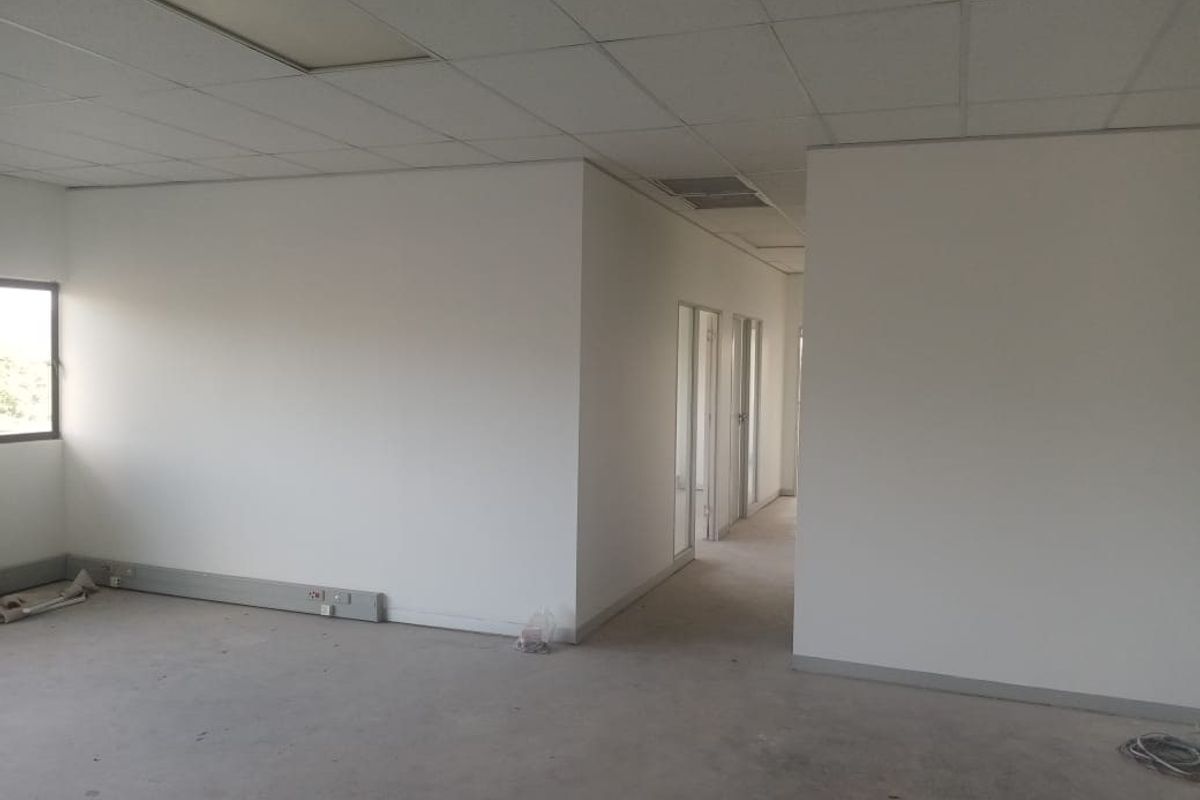 An empty commercial office space featuring a suspended ceiling, glass partition doors, and perimeter skirting trunking, ready for tenant fit-out.