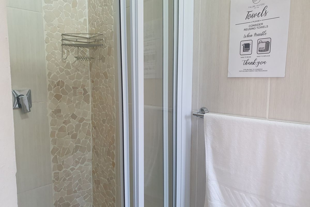 A clean bathroom shower area featuring a glass enclosure, tiled wall accents, and a chrome shower mixer.