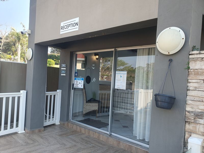 Entrance area featuring a sliding glass door, tiled patio flooring, and stone cladding accents on the exterior facade.